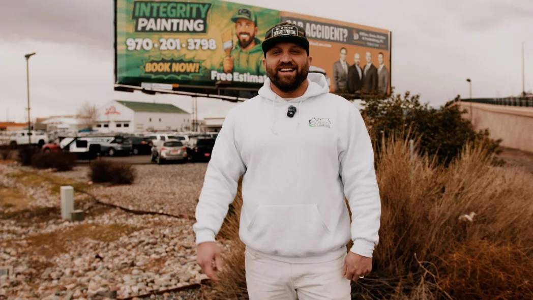 Daniel Thayer beside the Integrity Painting billboard in Grand Junction